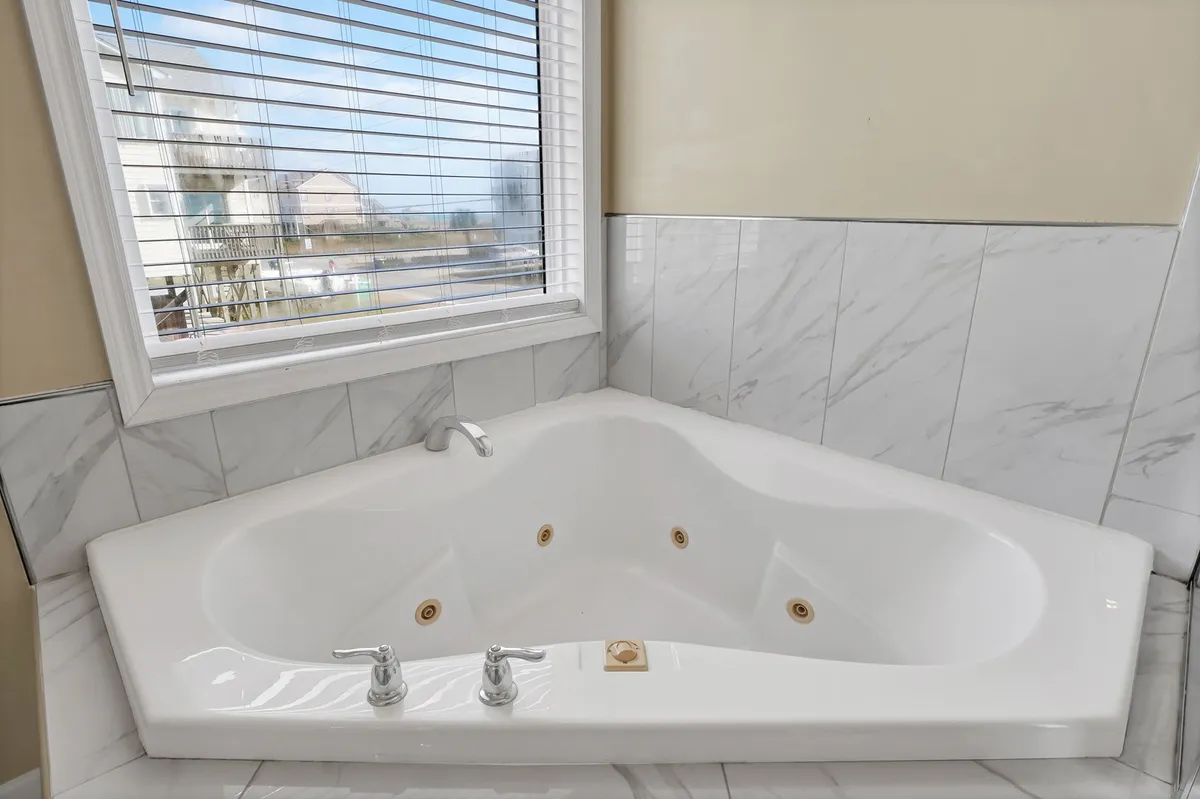 Inside, a corner jacuzzi tub with marble tiles sits beside a window, inviting long, luxurious soaks. The setup is designed for relaxation and self-care, making it an ideal retreat after a day exploring the shore.