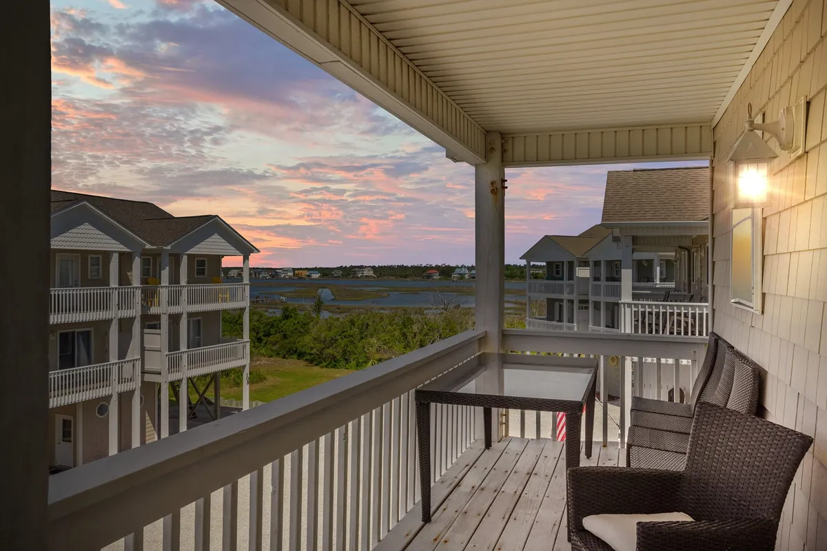 A balcony offers a sweeping view of the landscape bathed in the warm glow of sunset. The scene highlights a calm, inviting setting ideal for unwinding with a book, sharing a quiet drink, or simply soaking in breathtaking vistas.