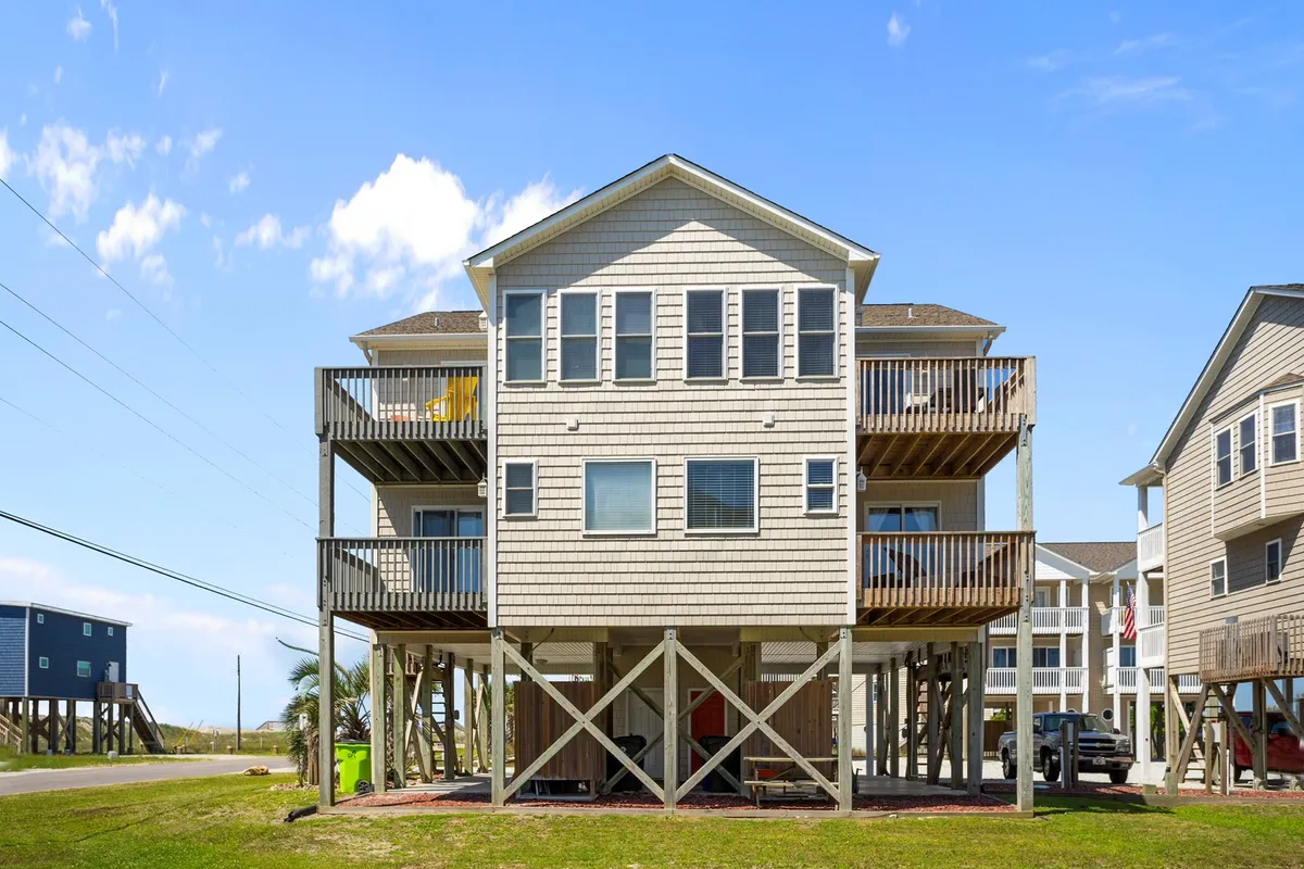 This exterior image features wooden decks, large windows, and an elevated structure, with ample outdoor space for gatherings. The scene exudes a cheerful mood perfect for family gatherings, outdoor dining, and relaxing in the sun.